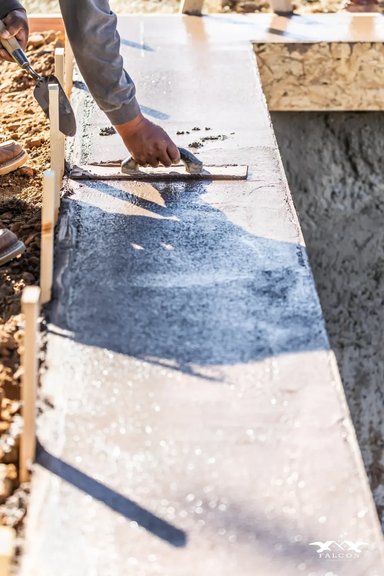 Concrete construction service in progress with contractor smoothing freshly poured concrete slab for durable walkway installation.