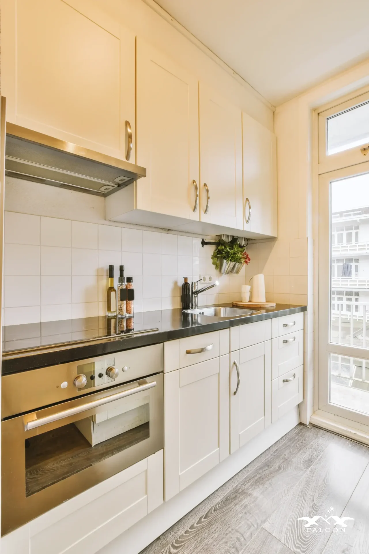 Small kitchen remodel featuring white cabinets, stainless steel oven, modern range hood, and sleek countertop with built-in sink.