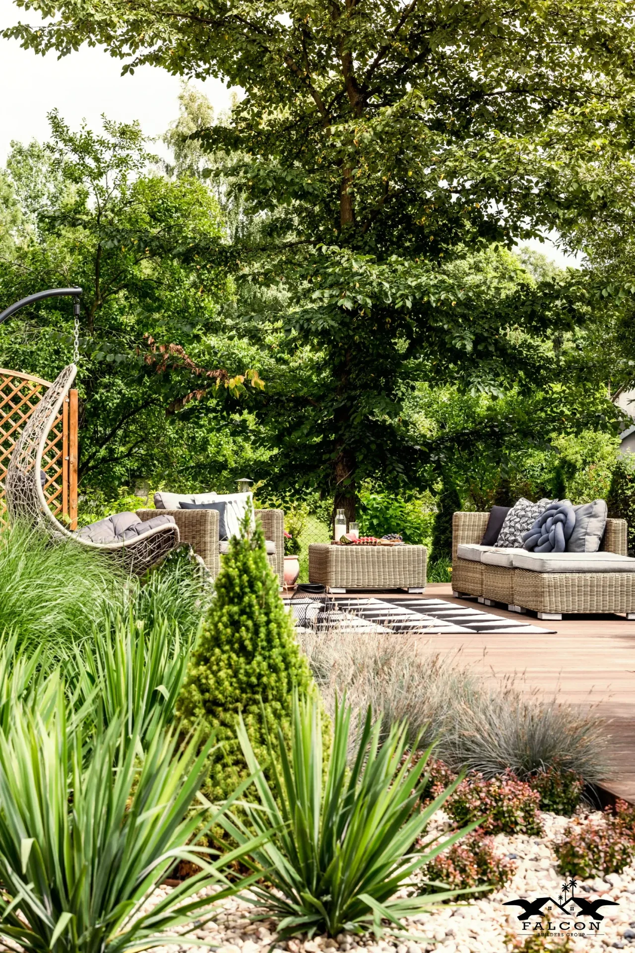 Landscaping service showcasing custom garden design with lush greenery, ornamental plants, decorative stone accents, and inviting backyard patio seating area.