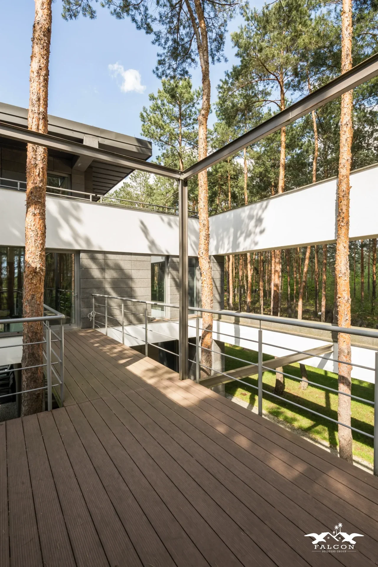 Deck construction project featuring elevated wood deck with modern metal railing integrated into contemporary home design surrounded by trees.