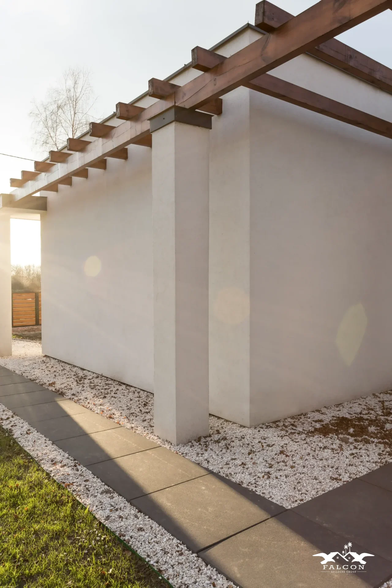 Concrete construction service featuring modern concrete walkway installation with clean edges and decorative gravel landscaping along home exterior.