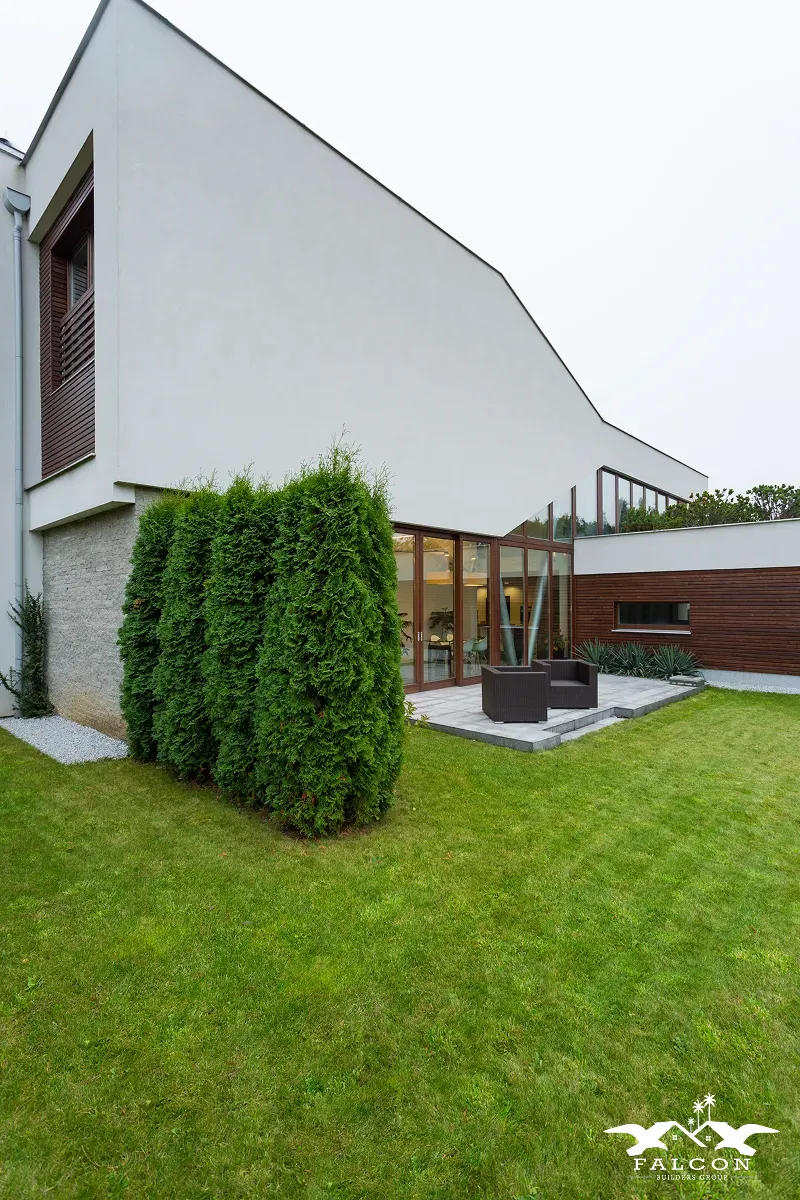 Landscaping service project featuring neatly trimmed privacy hedges, manicured green lawn, and modern patio design enhancing backyard outdoor living space.